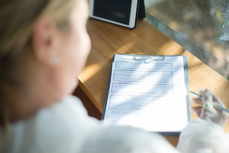 Person filling out a paper application form with a pen, illustrative of completing a housing authority pre-application